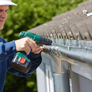 Indianapolis Roofing Contractors – Gutters and Gutter Protection Man with drill installing Gutter Protection