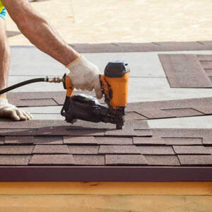 Plainfield roof inspection Nail gun with hand and arm nailing down a roofing tile.