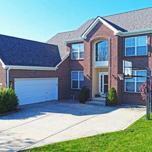 Zionsville Roofers Two story brick faced home with garage in front.