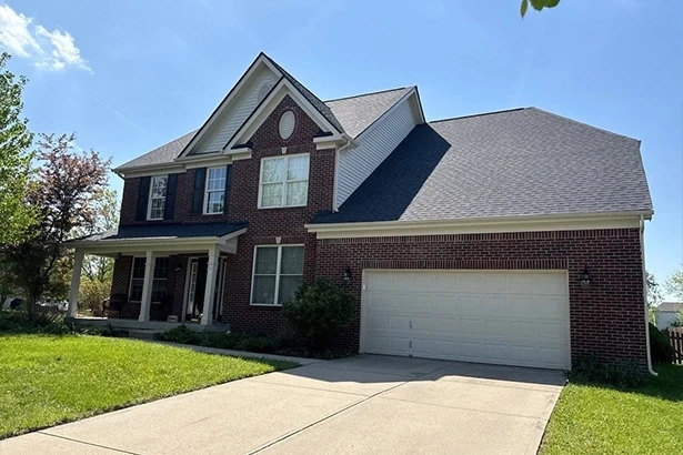 Zionsville roof repair by total replacement on two-story brick home with gray asphalt shingle roof and attached garage