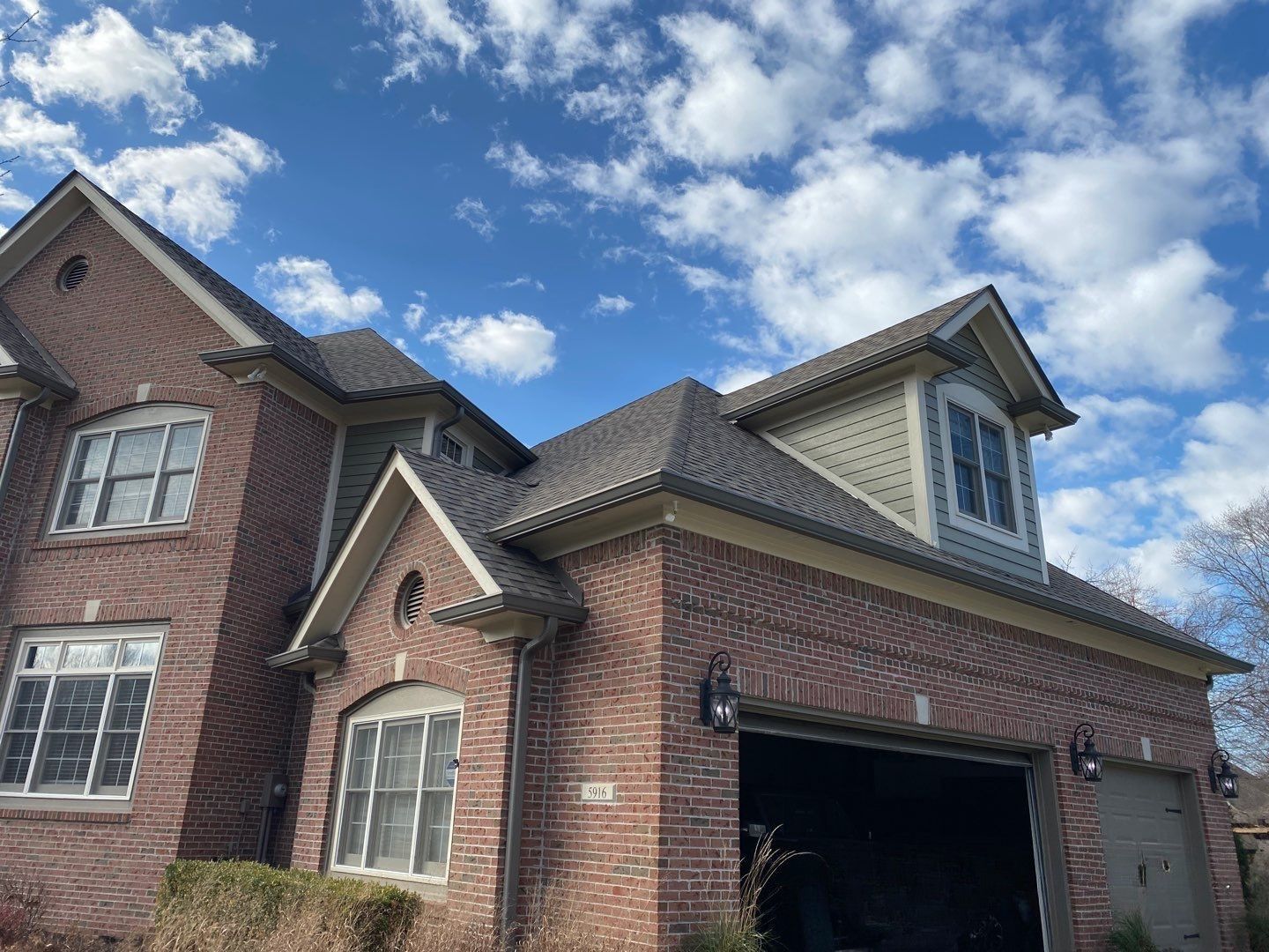 Completed roof repair on a multi-pitch brick home with dormers in Carmel, IN by Robert Stevens Roofing