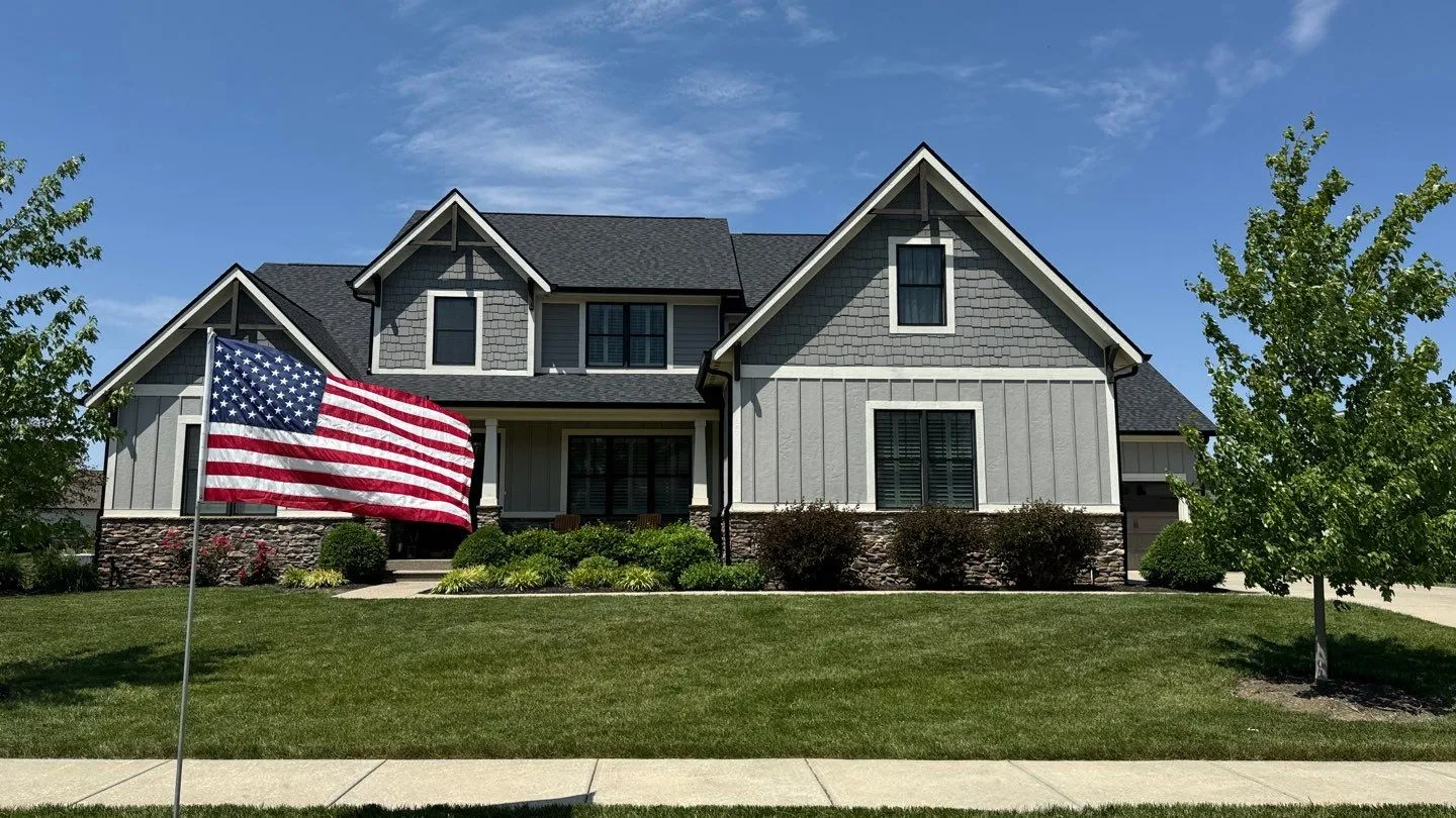 Westfield roofing project | Modern farmhouse roof replacement Modern farmhouse in Westfield with dark slate roof, board and batten siding, stone accents, and American flag